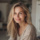Femme souriante aux cheveux blonds à l'intérieur.